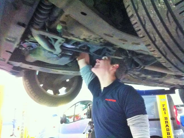 A mechanic working under a car on the lift
